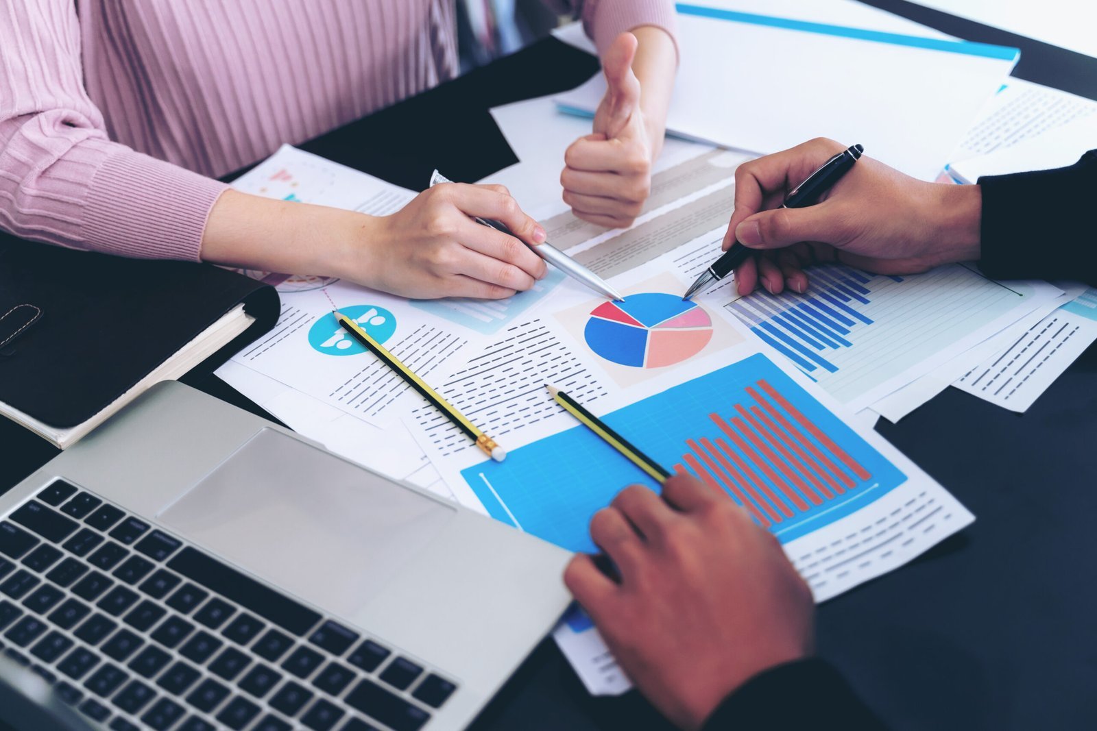 Team reviewing project reports, charts, and performance graphs during a planning meeting, representing construction project planning, collaboration, and data-driven decision-making.