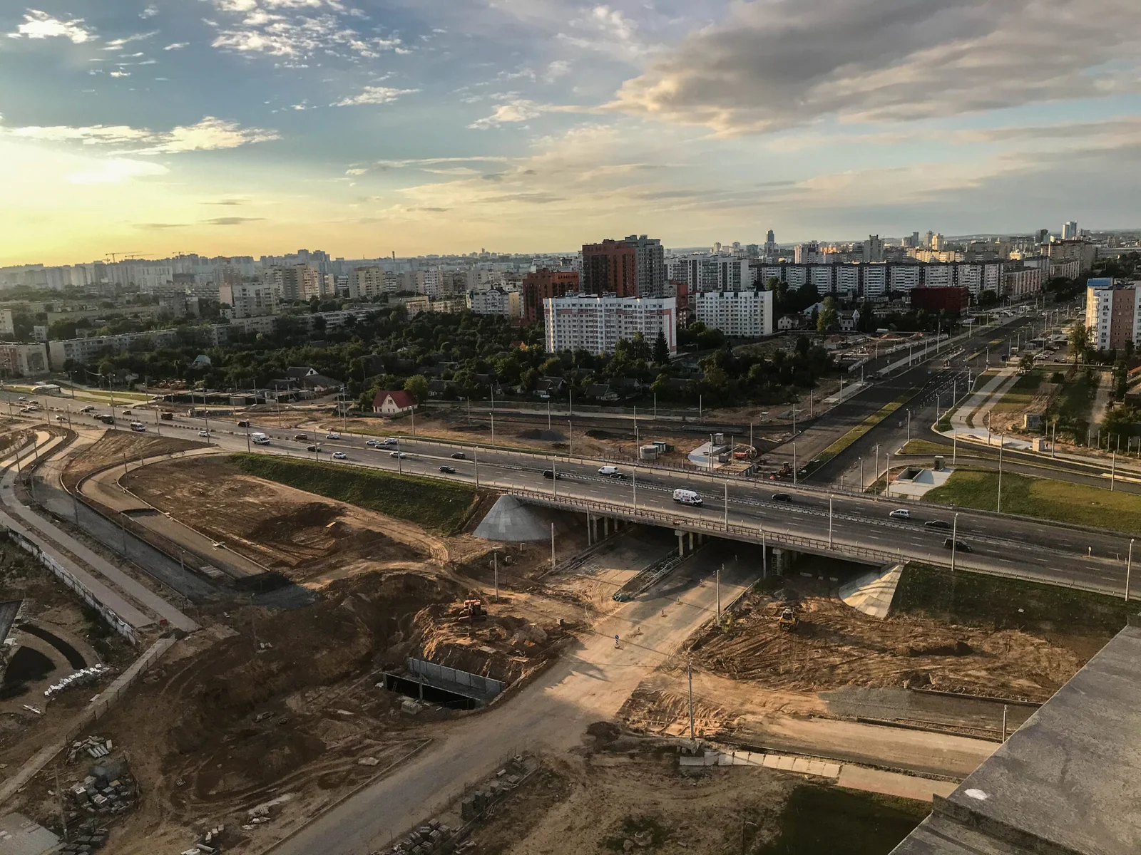 Aerial view of a newly constructed highway overpass with roads, bridge infrastructure, and an urban skyline, showcasing modern civil infrastructure development for efficient transportation and city connectivity.