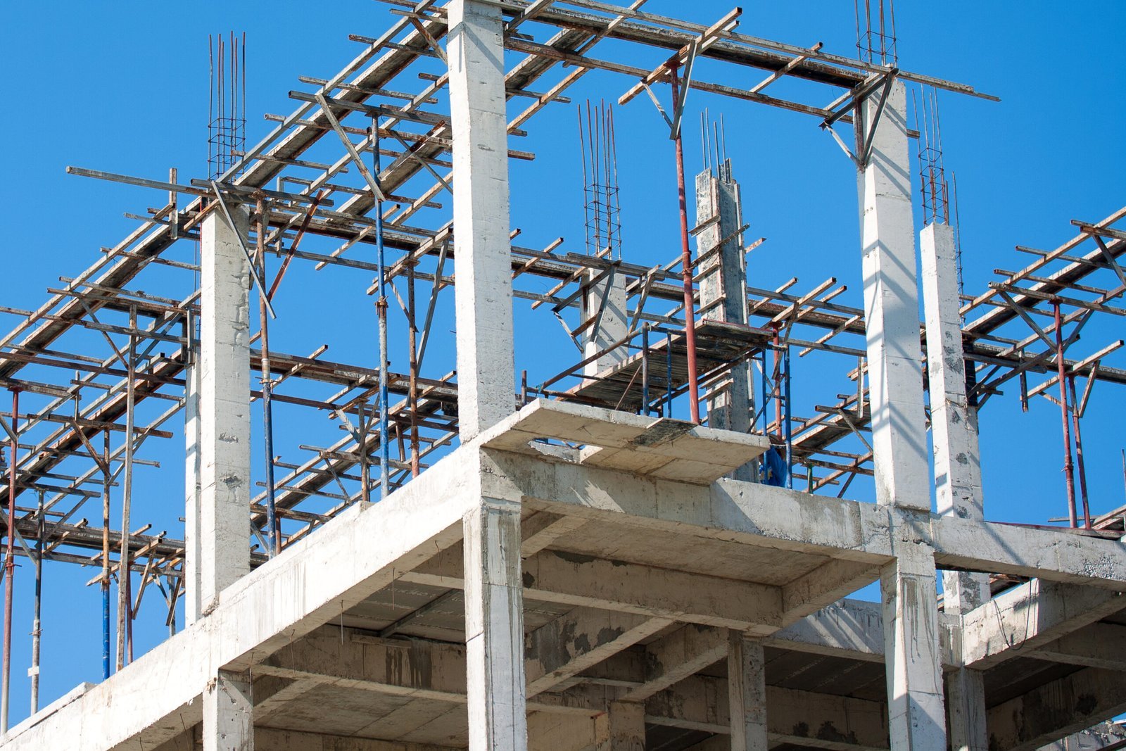 Reinforced concrete building framework under construction with structural columns and scaffolding, illustrating commercial building construction.