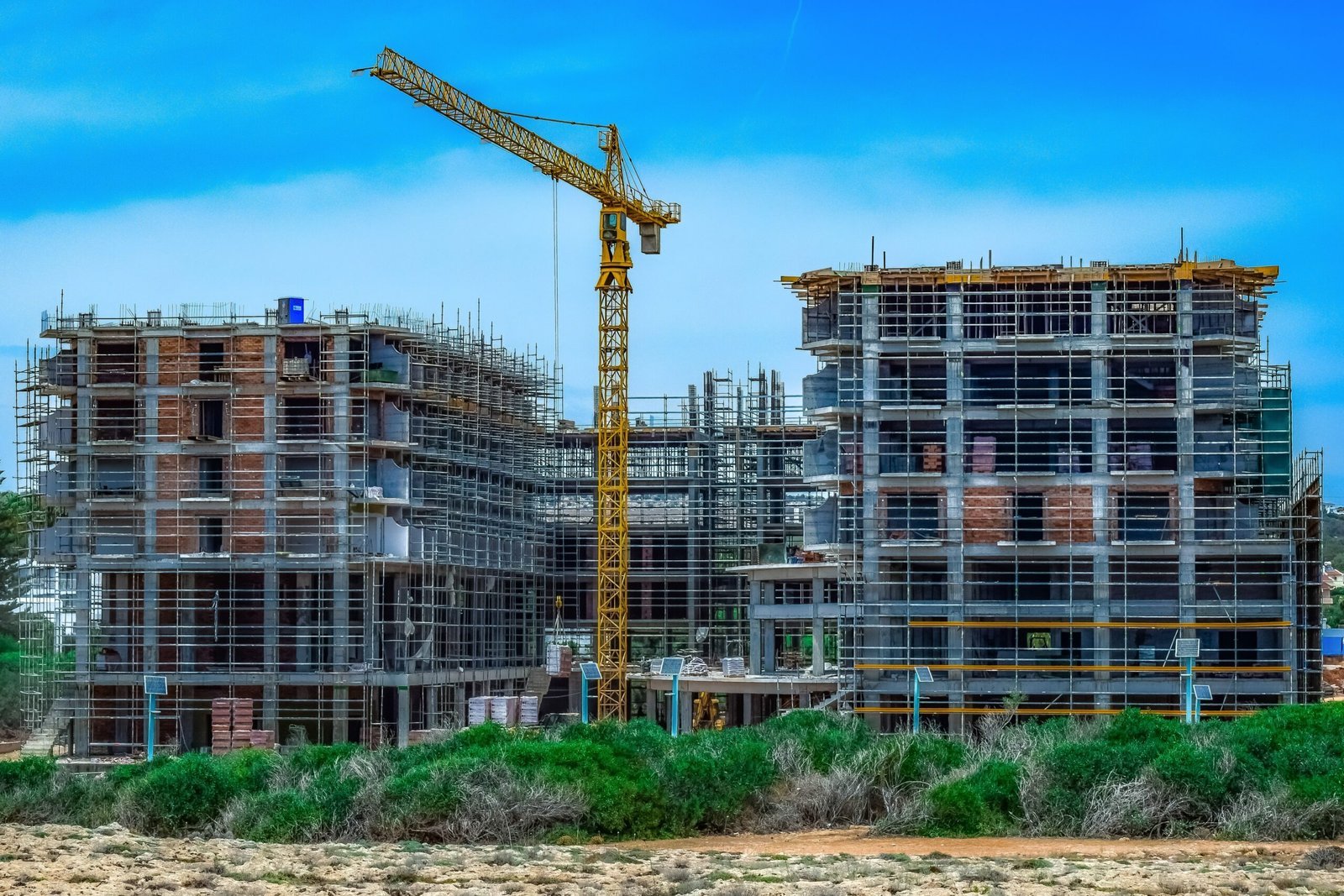 Large residential construction project with cranes and structural framework, representing infrastructure development for real estate and housing projects.
